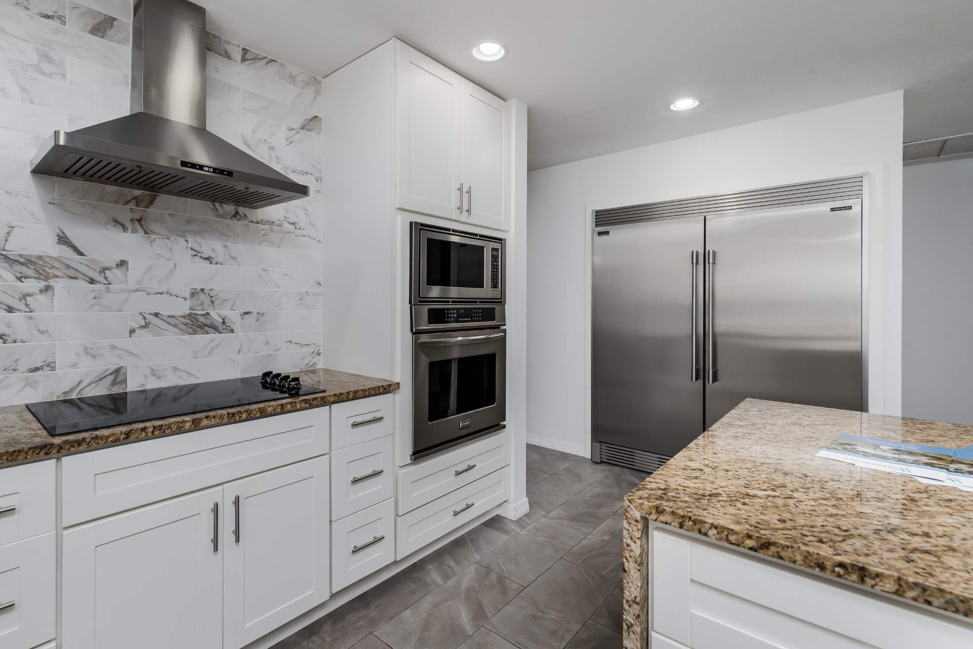 Kitchen with stainless appliances, wall oven, and marble backsplash